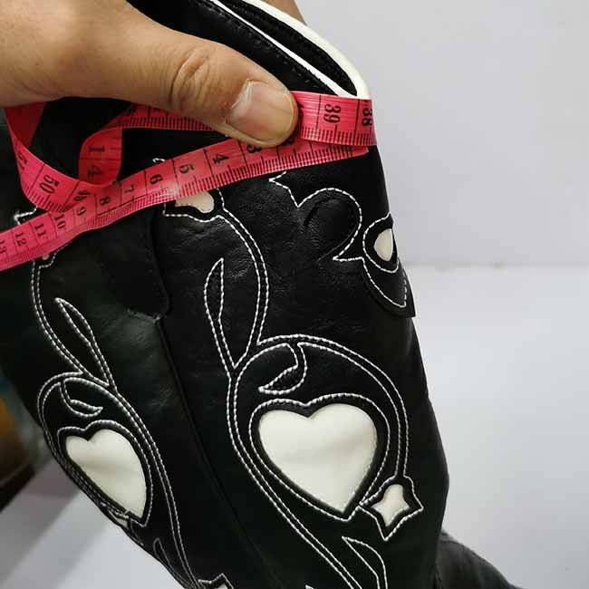 Measuring the height of black embroidered cowgirl boots for women with a tape measure