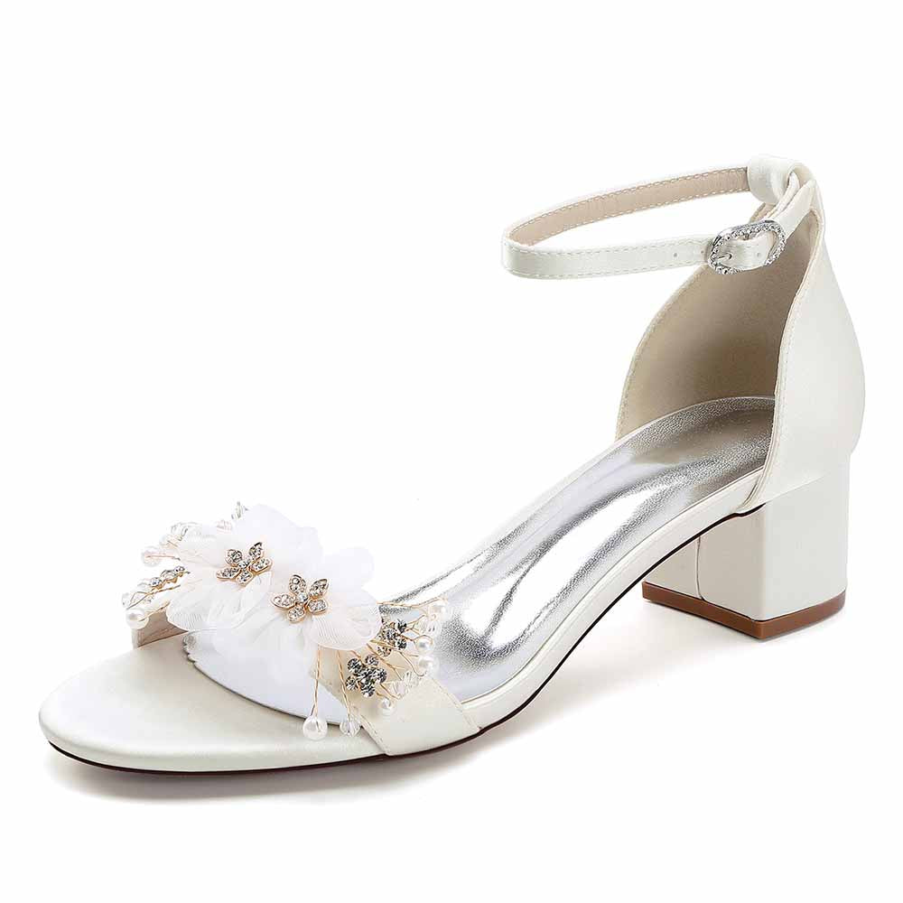 Elegant chunky heeled sandals for brides featuring floral accents and an ankle strap in white