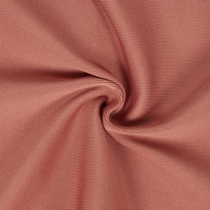 Soft fabric texture of a strappy bodycon dress with tassel details in a warm hue