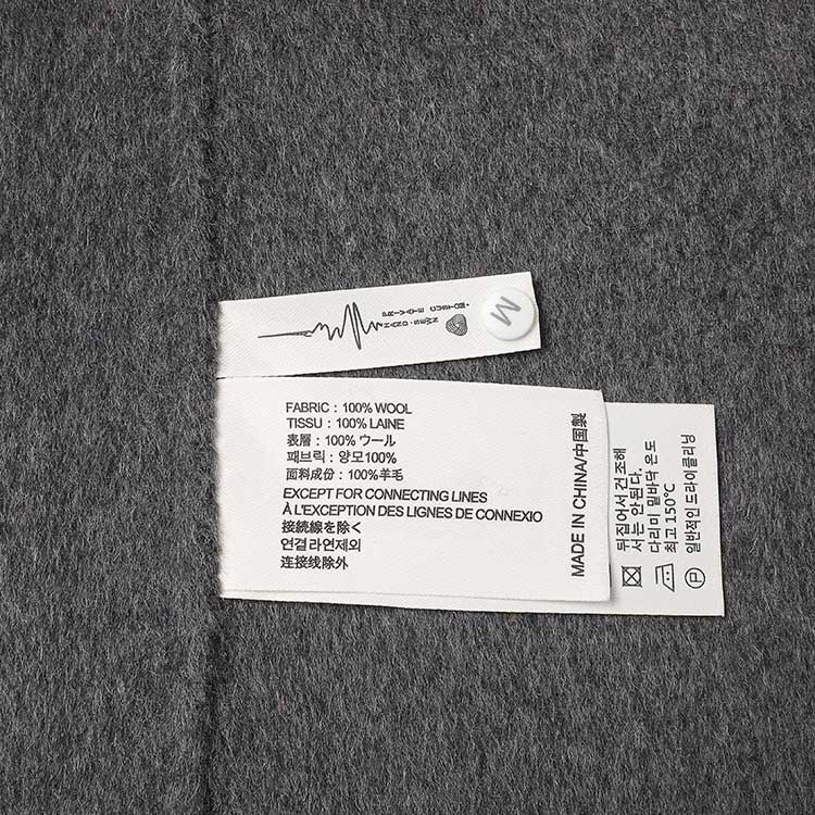 Label of women's double-breasted grey coat showing fabric details and care instructions