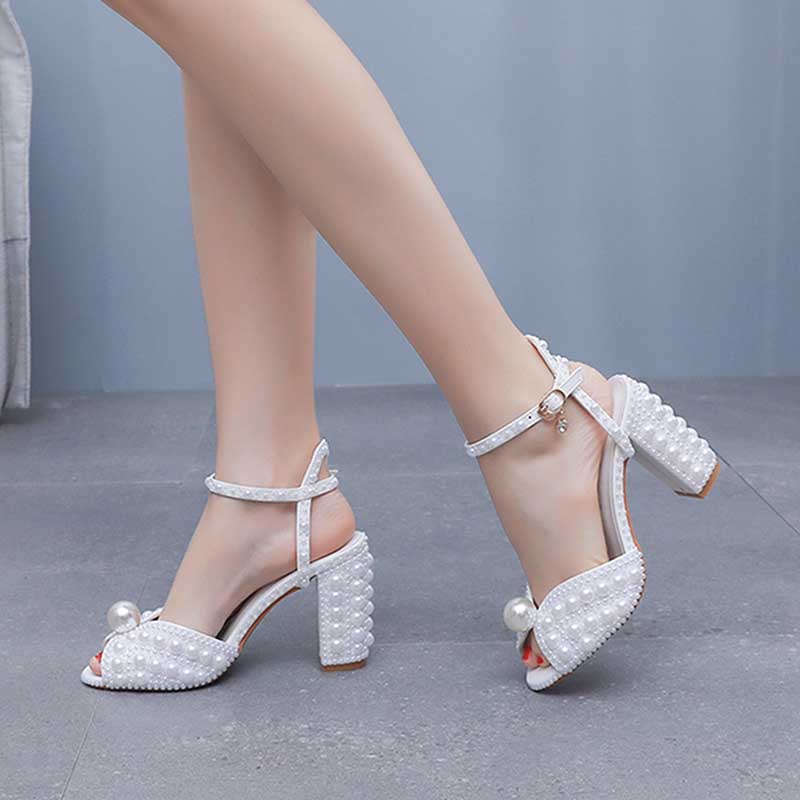 Stylish white chunky wedding sandals with pearl accents and ankle strap for a trendy bridal look