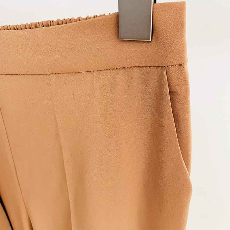 Close-up of women's camel pantsuit for work highlighting the waistband and fabric texture