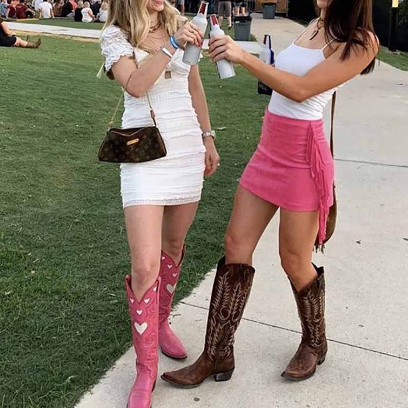 Two women wearing stylish outfits and women's embroidery heart cowgirl boots at an outdoor event