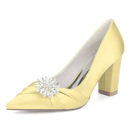 Yellow high-heeled shoe with a decorative crystal on a white background