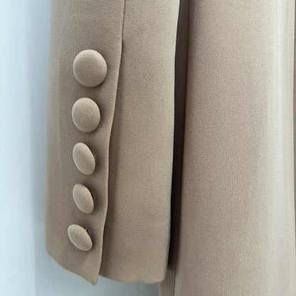 Close-up of a beige or taupe fabric garment detail showing a sleeve or panel with five large round buttons on the left side and smooth matching fabric on the right.