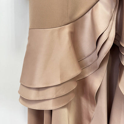 Close-up of a taupe-beige dress with a structured bodice and layered draped satin ruffle skirt details.