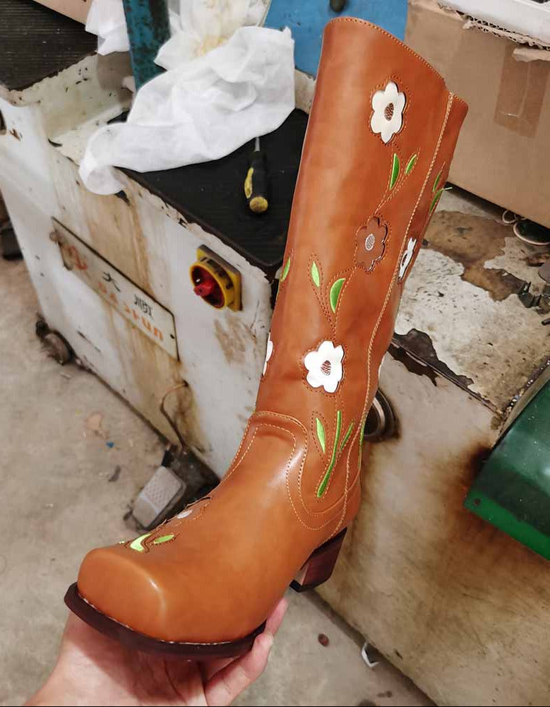 Brown boot with floral designs held in a workshop setting