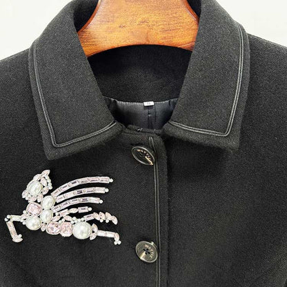 Elegant women's winter wool coat in black featuring a decorative bejeweled brooch