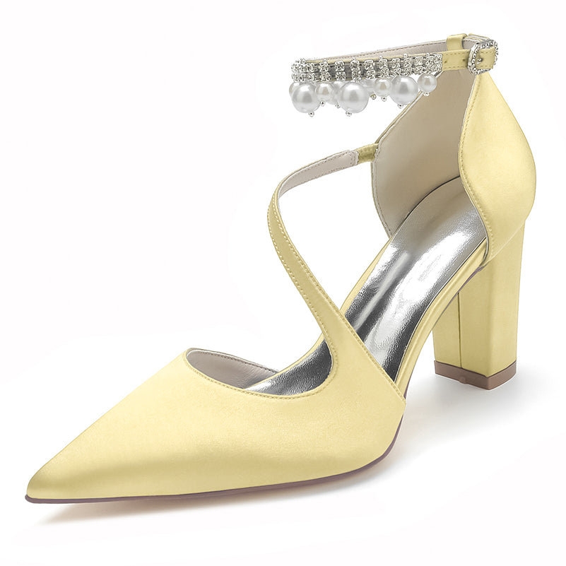 Yellow high-heeled shoe with pearl and crystal strap on a white background