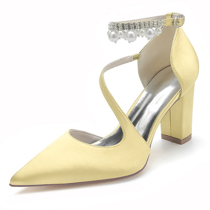 Yellow high-heeled shoe with pearl and crystal strap on a white background