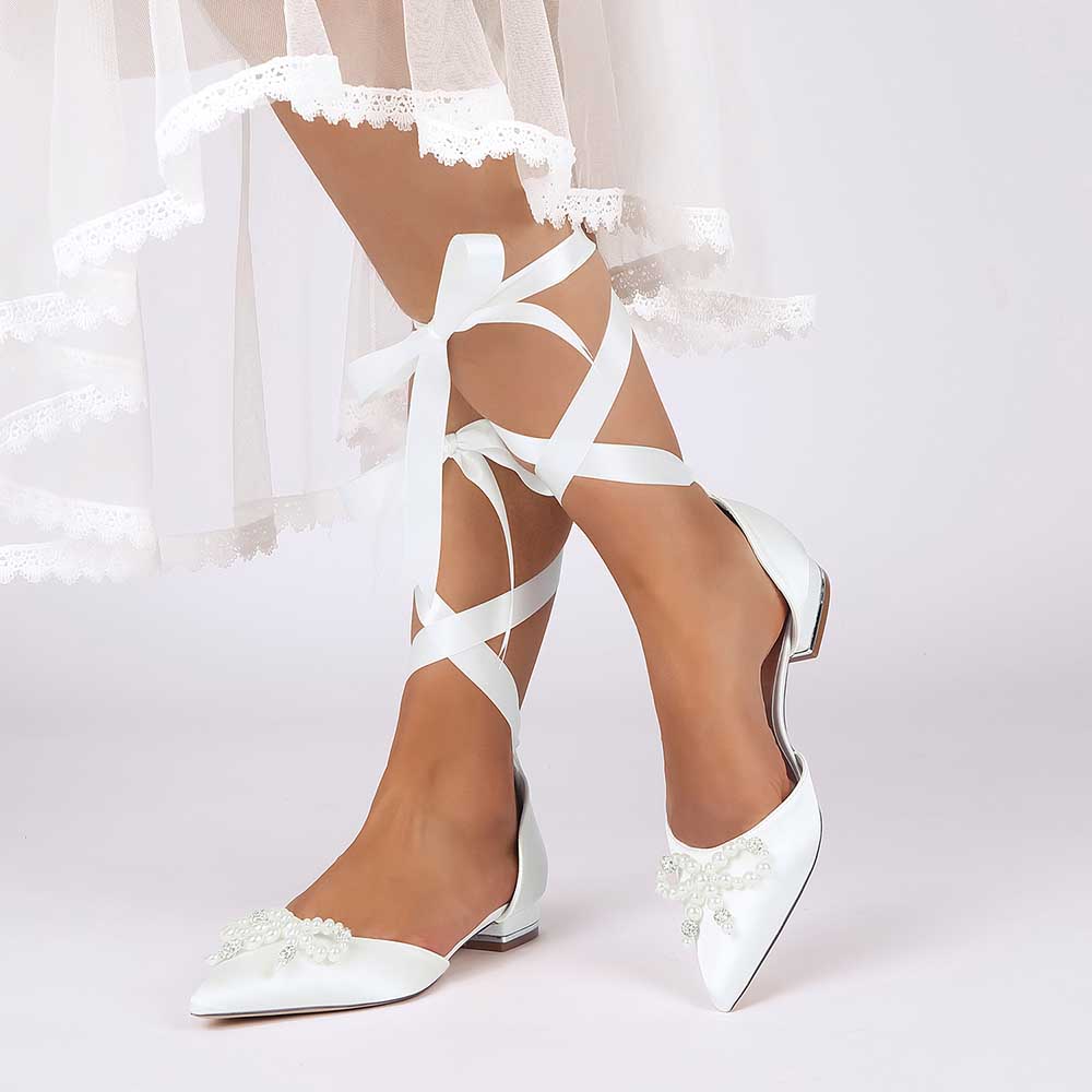 White bridal ankle strap flat shoes with lace ribbons and bow detail for elegant bridal outfits