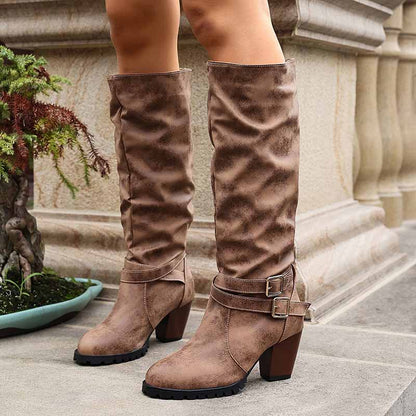 Brown chunky heel knee-high boots with a stylish slouchy design and adjustable buckles