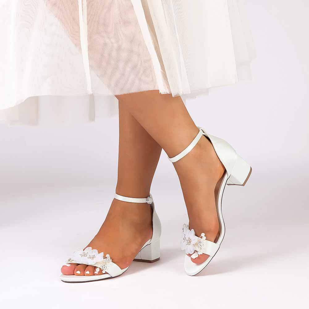 White chunky heeled sandals for brides featuring floral accents and ankle strap