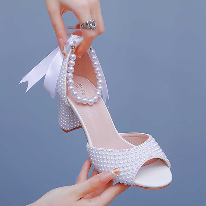 White chunky lace up bridal shoes adorned with pearls and a ribbon for a stylish wedding look