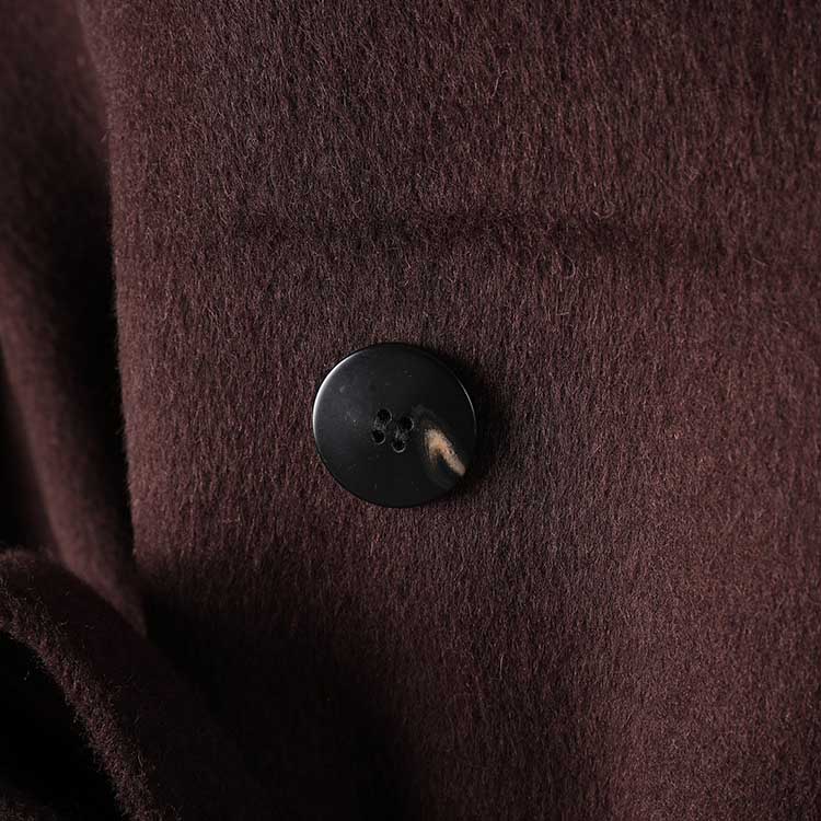 Close-up of button detail on collarless double belted cashmere coat in rich brown color