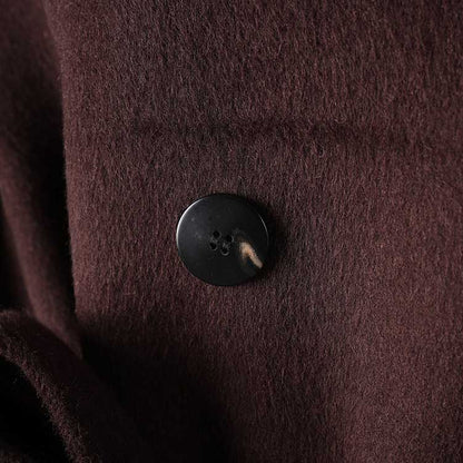 Close-up of button detail on collarless double belted cashmere coat in rich brown color