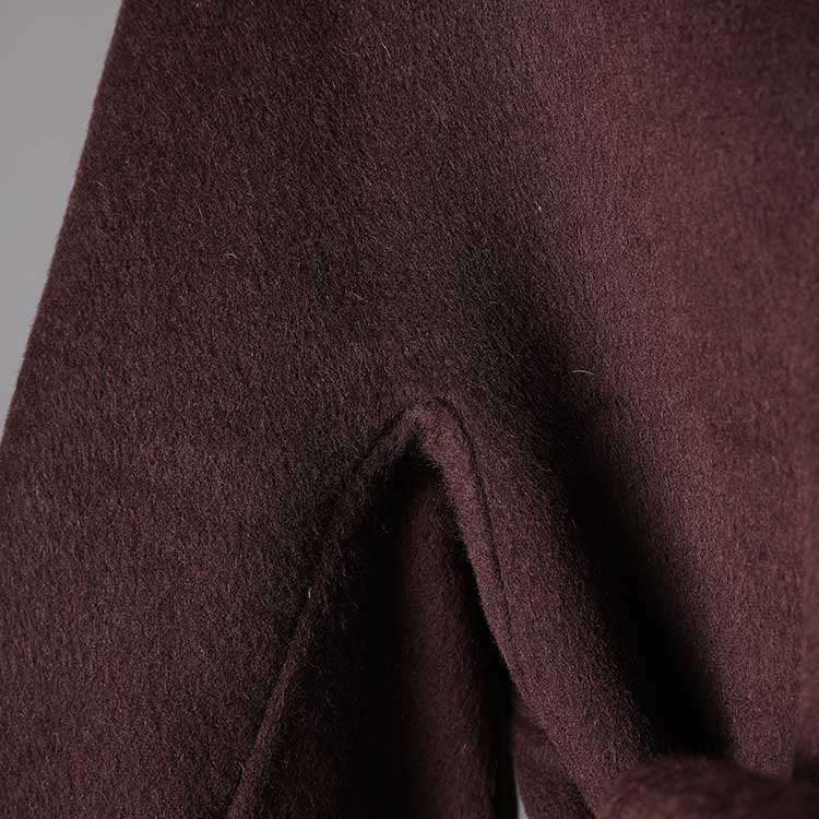 Close-up of a collarless double belted cashmere coat in a rich brown fabric