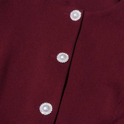 Close-up of buttons on a collarless women's midi skirt set in rich burgundy fabric