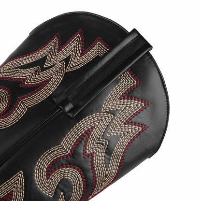 Close-up of colorful embroidered cowgirl boots featuring intricate stitching detail on a black leather background