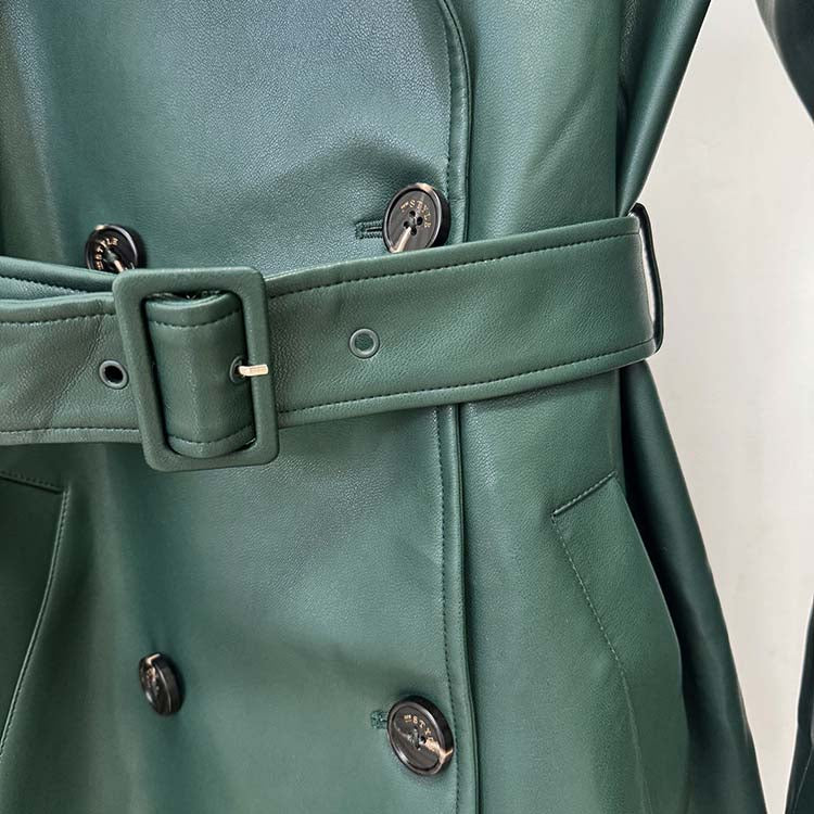 Close-up of a double breasted faux leather trench coat in green with stylish belt and buttons