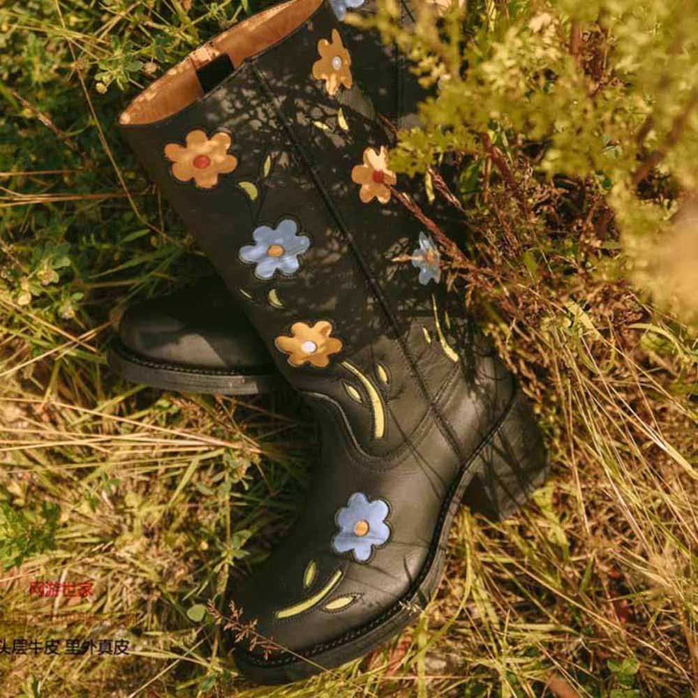 Floral embroidered boots in black with colorful flower designs against a natural backdrop