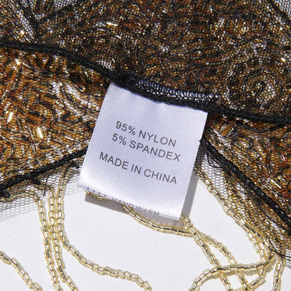 Close-up of gatsby style beaded fringe cape showing fabric details and care label