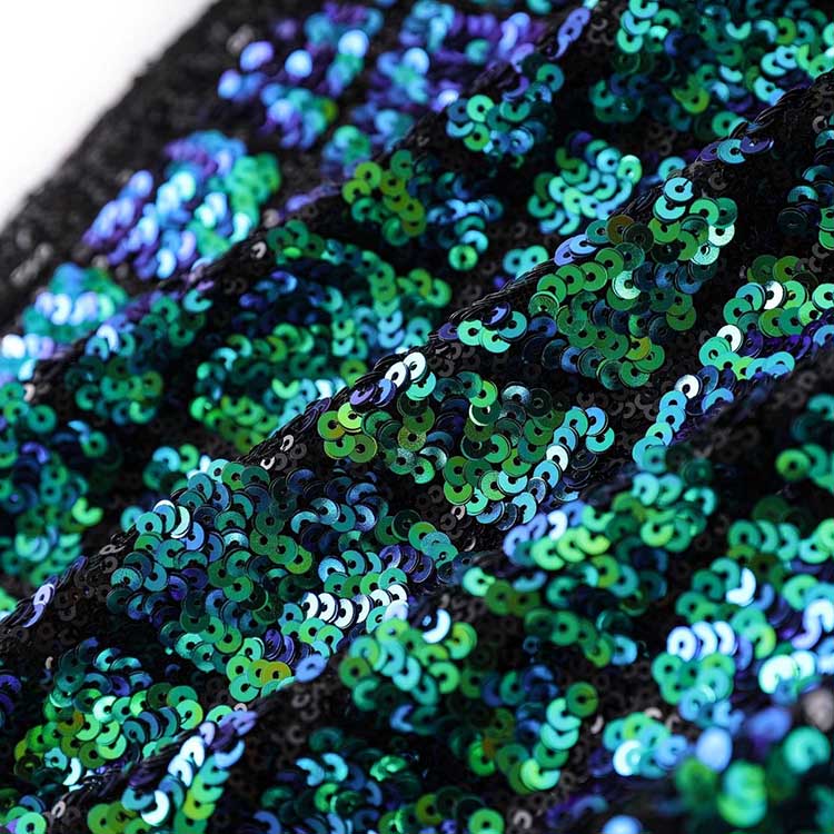 Close-up of a green sequin mini dress featuring vibrant sequins with shades of green and blue