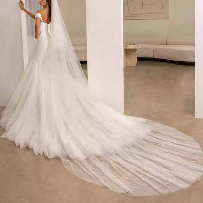 Elegant lace satin off shoulder bridal gown with a flowing train and intricate back details