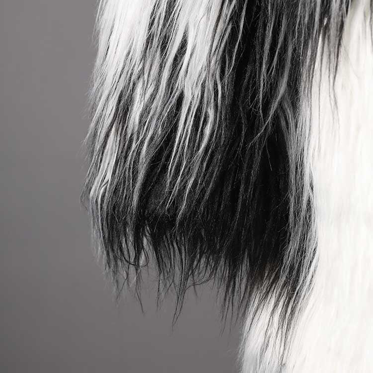 Textured close-up of long faux fur coat for women, showcasing luxurious black and white fur
