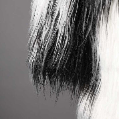 Textured close-up of long faux fur coat for women, showcasing luxurious black and white fur