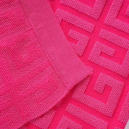 Close-up of a long knitted cardigan set featuring vibrant pink fabric and textured patterns