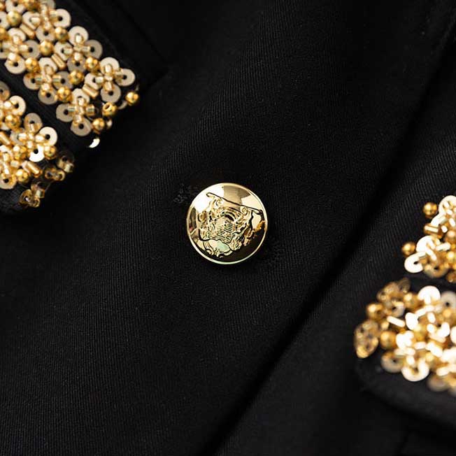 Close-up of luxury black skirt suit for weddings featuring intricate gold detailing and elegant buttons
