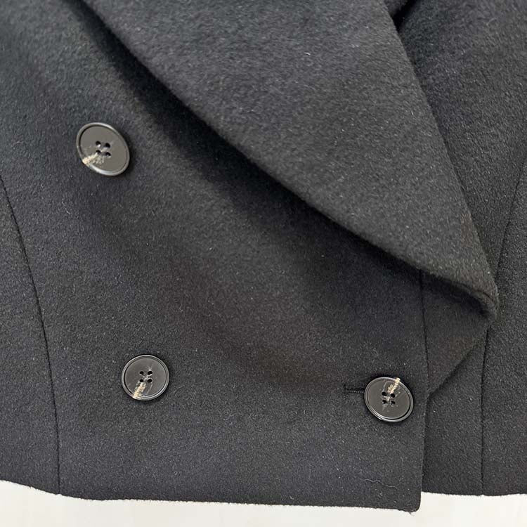 Close-up of a black minimalist double-breasted wool coat with stylish buttons