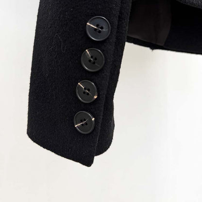 Close-up of black buttons on a minimalist double-breasted wool coat showcasing detailed craftsmanship