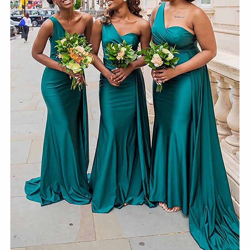 Elegant one shoulder satin bridesmaid dress in green, worn by three bridesmaids holding bouquets