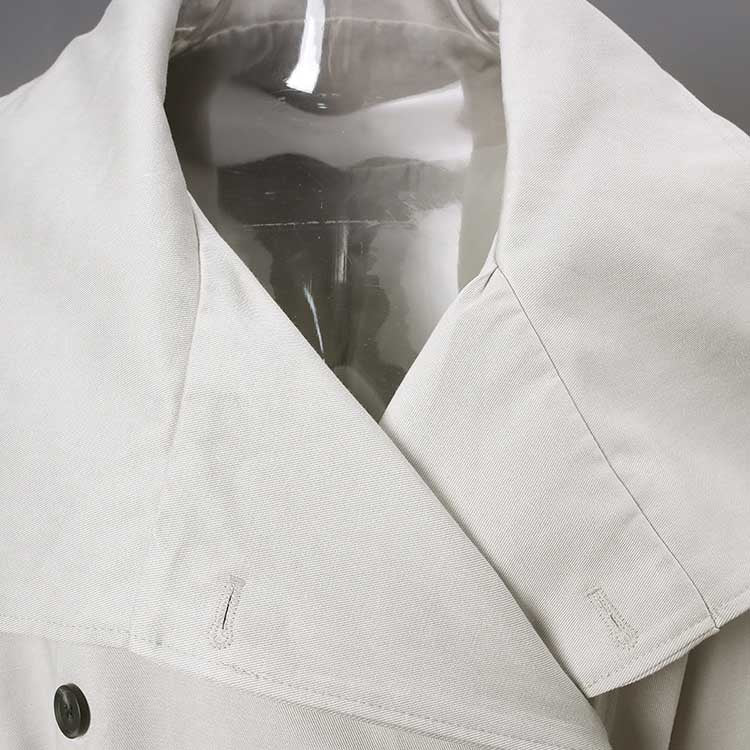 Detail of an oversize women's trench coat featuring a stylish collar and button closure