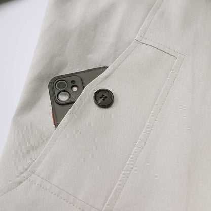 Detail of the oversize women's trench coat showing a button and pocket with a smartphone
