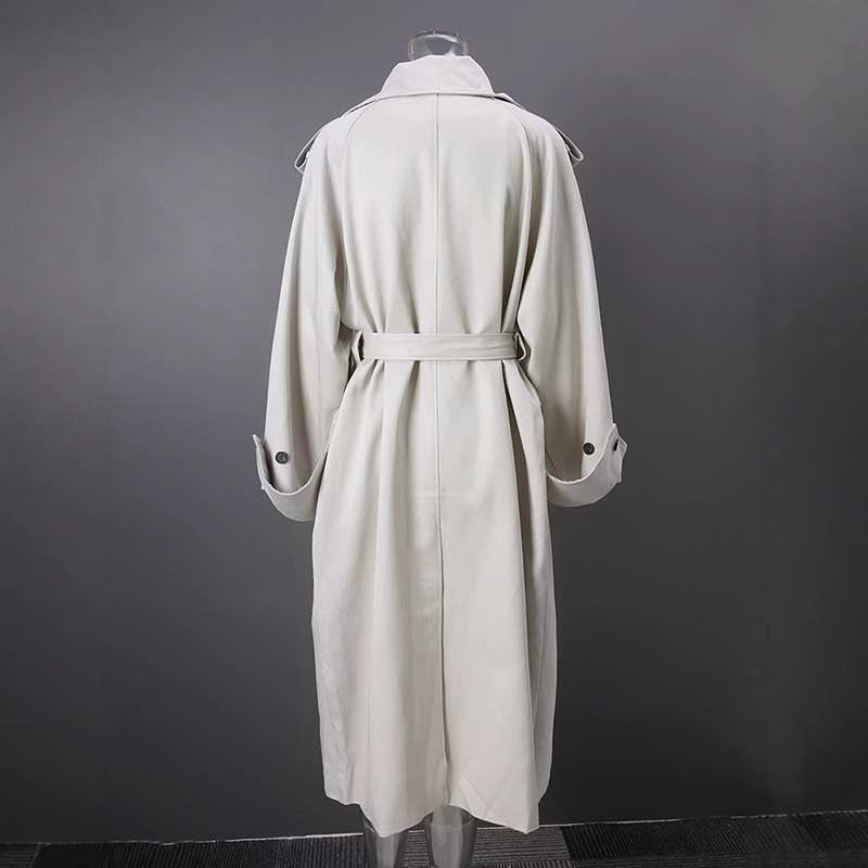 Back view of an oversize women's trench coat in light beige with a tied belt and buttoned sleeves
