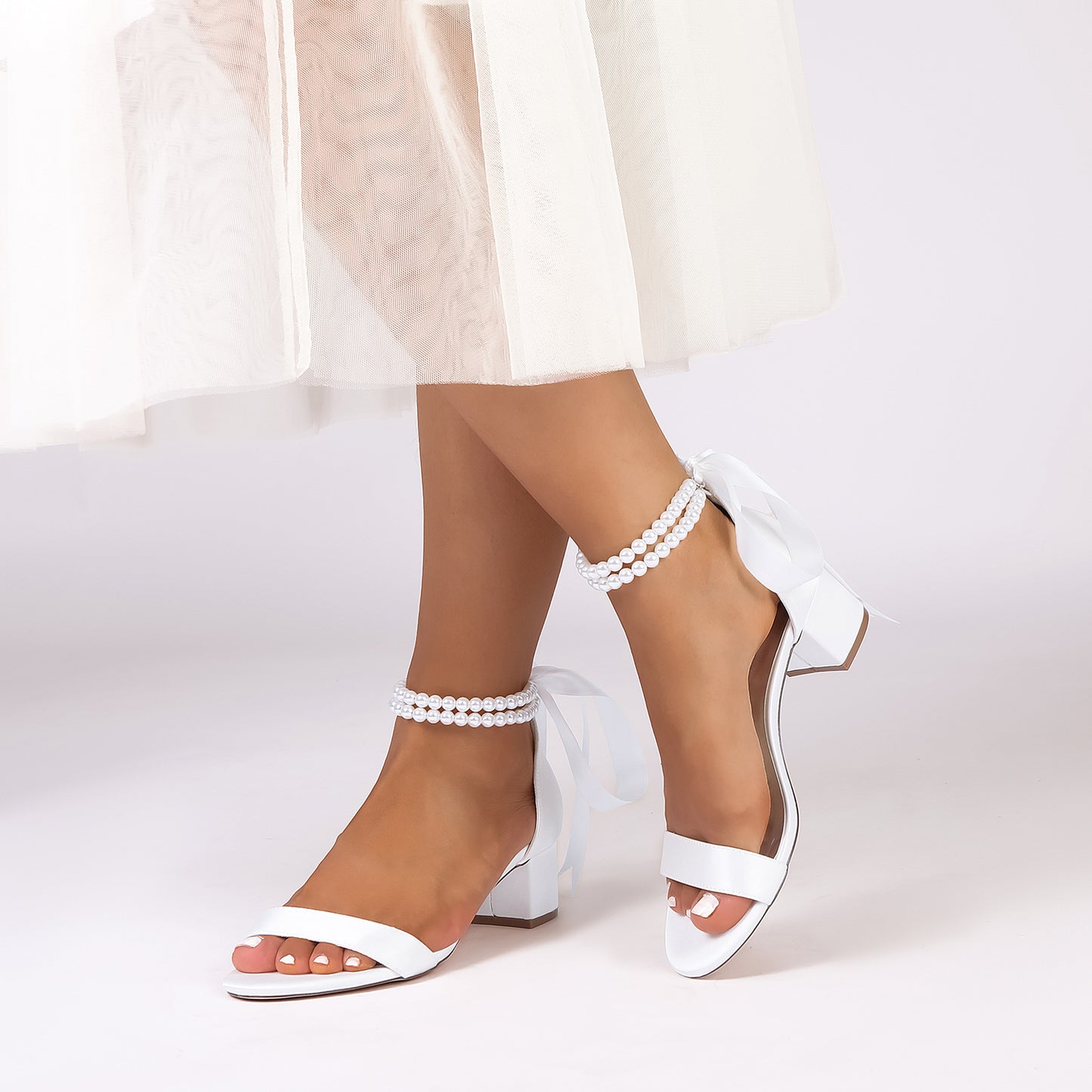 Elegant pearl lace-up bridal sandals with a bow and ankle strap, perfect for weddings