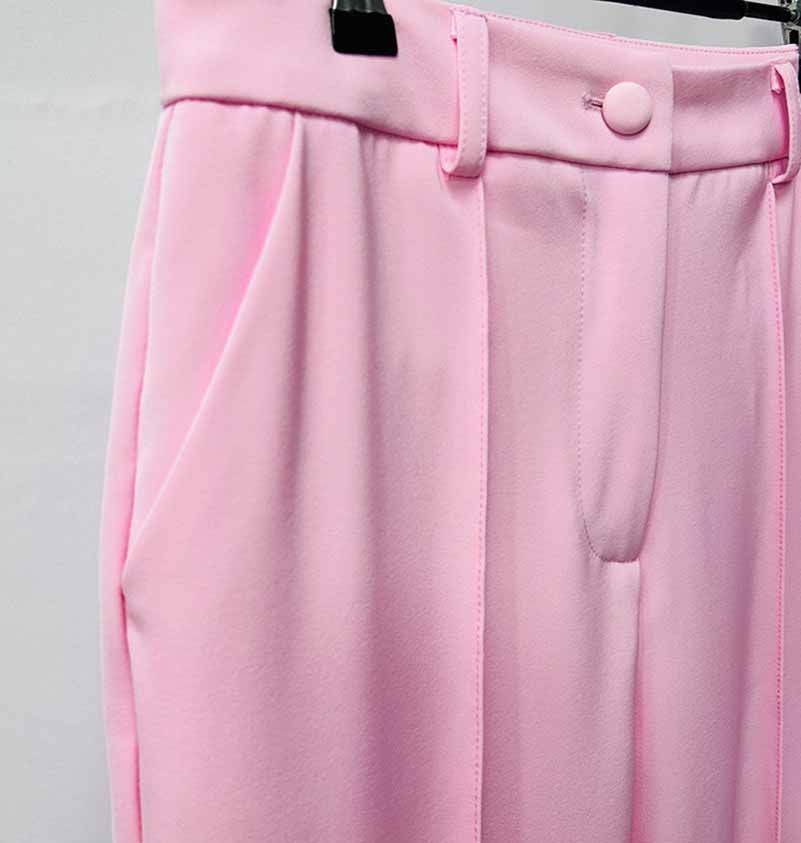 Detail of a pink women's pantsuit for wedding featuring pleated front and tailored fit