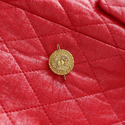 Detailed view of a gold button on a red faux leather mini dress with quilted texture