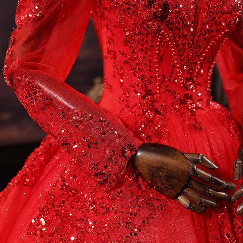 Close-up view of a sparkly red ball gown wedding dress featuring intricate beadwork and flowing sleeves