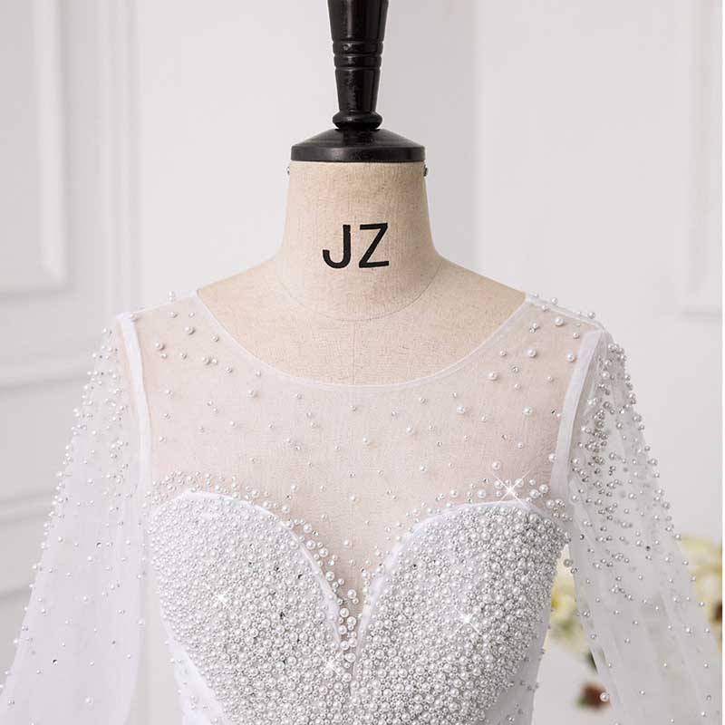 Elegant sweetheart tulle wedding dress with pearl detailing and long sheer sleeves