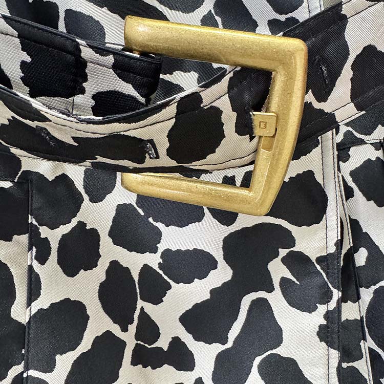 Close-up of a tailored animal print long coat featuring a gold buckle for stylish detailing