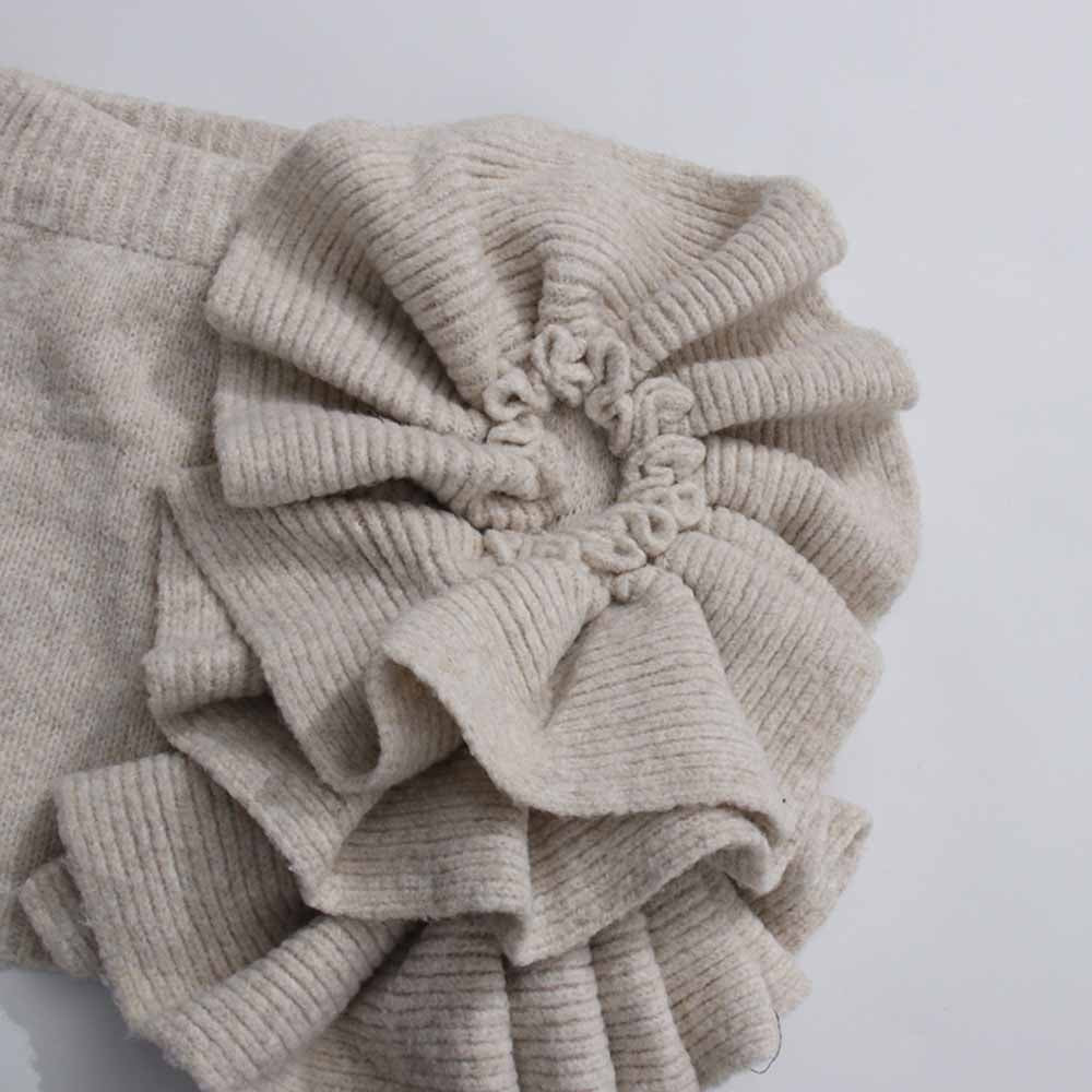 Textured detail of a beige three piece women's sweater set featuring ruffled sleeves for a stylish look