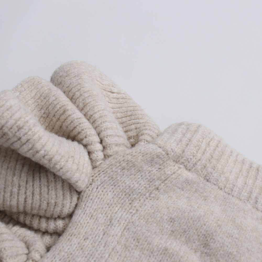 Close-up of the sleeve detail of a three piece women's sweater set in a soft beige color