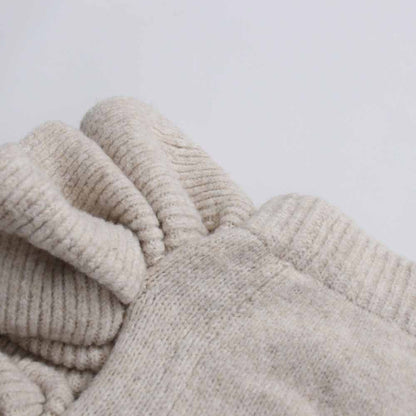 Close-up of the sleeve detail of a three piece women's sweater set in a soft beige color