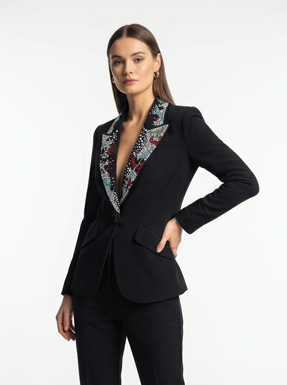 Woman wearing a black suit with a patterned collar on a white background