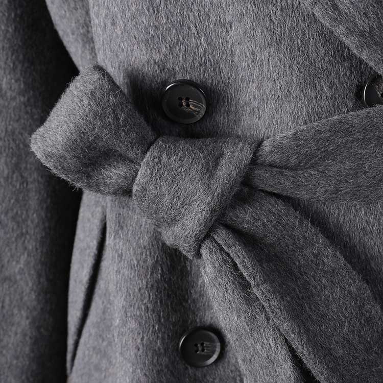Close-up of a women's double-breasted grey coat with a stylish belt and button details