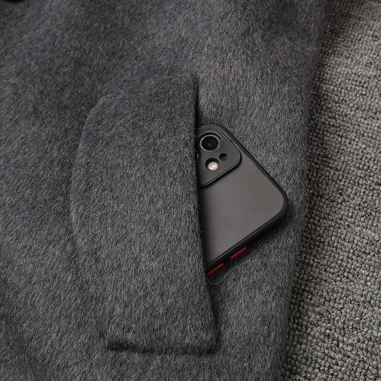 Close-up of a women's double-breasted grey coat with a smartphone in the pocket